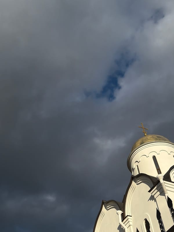 Golden dome with cross photographed against dramatic sky