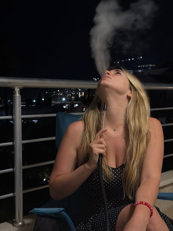 Woman enjoys evening hookah session on Budva balcony