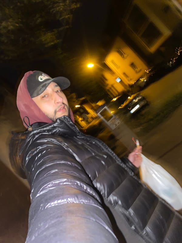 Man in maroon hoodie photographed in dimly lit Schiltigheim setting