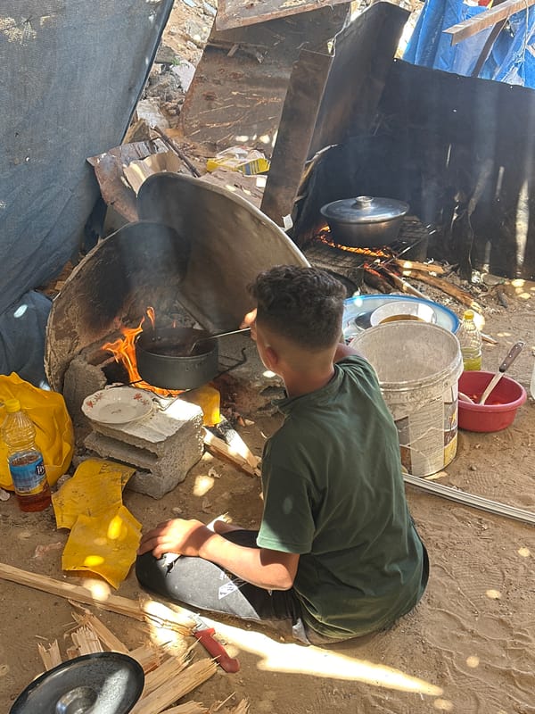 Person cooks over makeshift fire in damaged Gaza area
