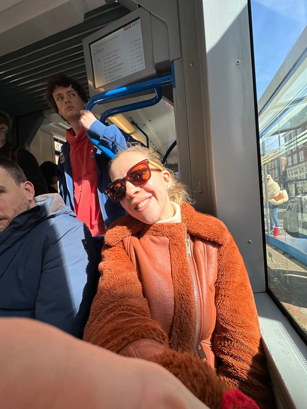 Woman smiles on Amsterdam tram during sunny morning commute