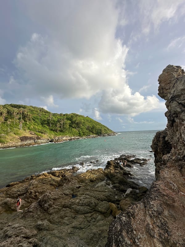 Rawai's rugged coastline: waves, cliffs, and a paraglider overhead