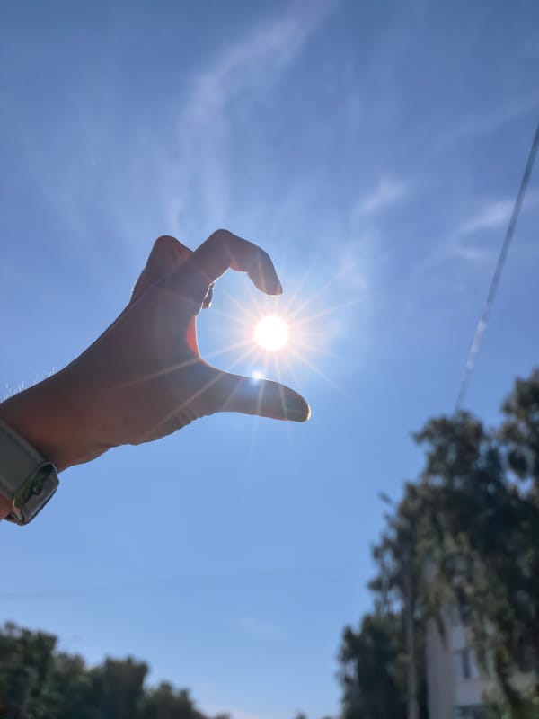 Hands against the sun and a vial on pebbled ground, Sterlitamak