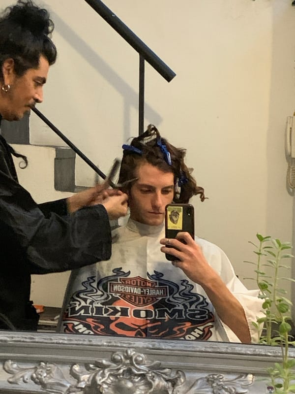 Mirror reflection captures two people, one holding scissors in Buenos Aires