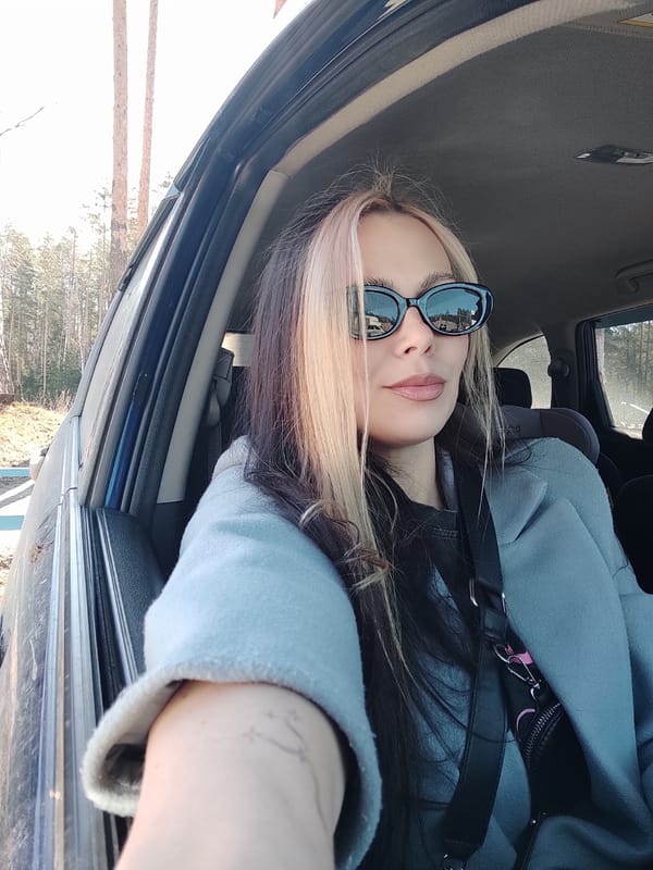 Woman takes selfie near pine-lined street in Noviy