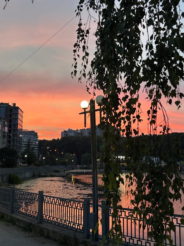Golden hour at Ternopil Pond, city reflected in still water