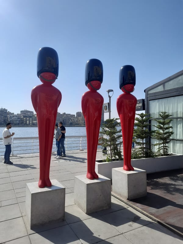 Red humanoid sculptures displayed along Cairo waterfront walkway