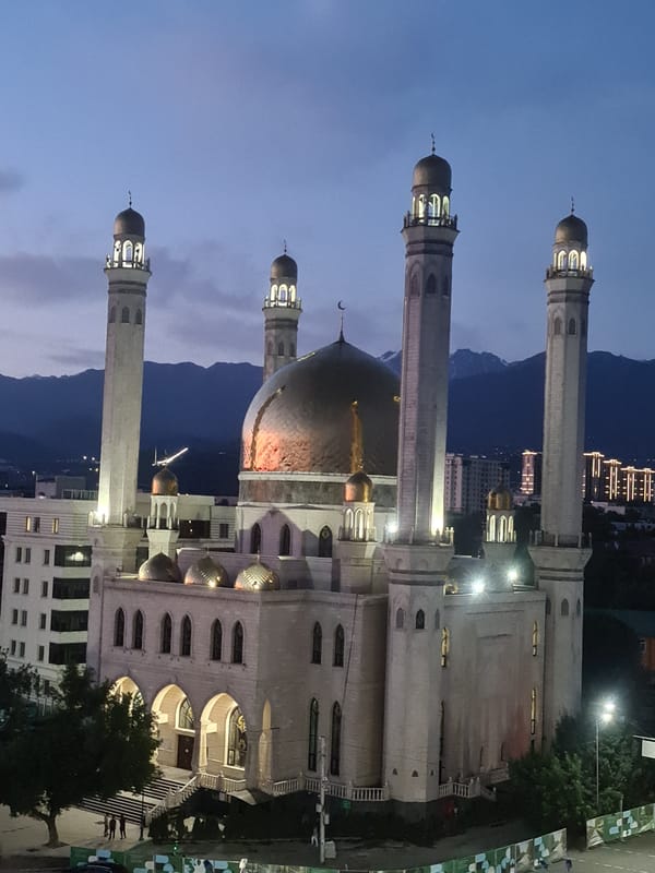 Almaty's Central Mosque glows at dusk alongside the city skyline