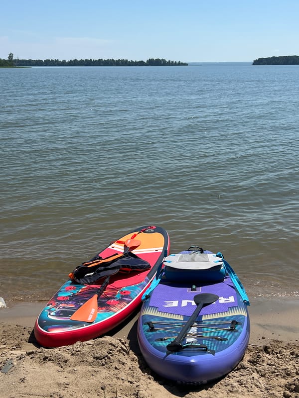 Paddleboards and gear lined up on a calm Russian lakeside