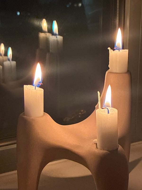 Three lit candles observed in London evening setting