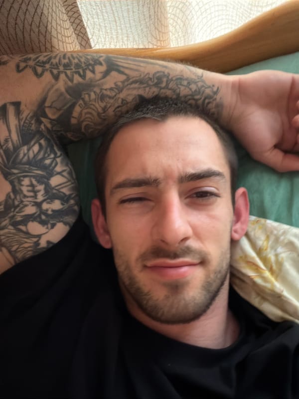 Tattooed man resting on bed in Plovdiv