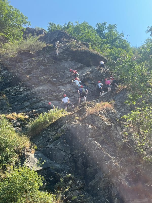 Via ferrata group climbs a steep cliff face in mountain terrain