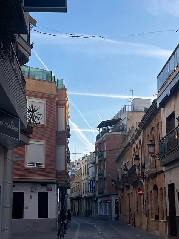 Aircraft contrails streak across morning skies over Paiporta, Spain