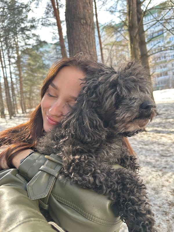 Woman embraces black dog in snowy forest setting