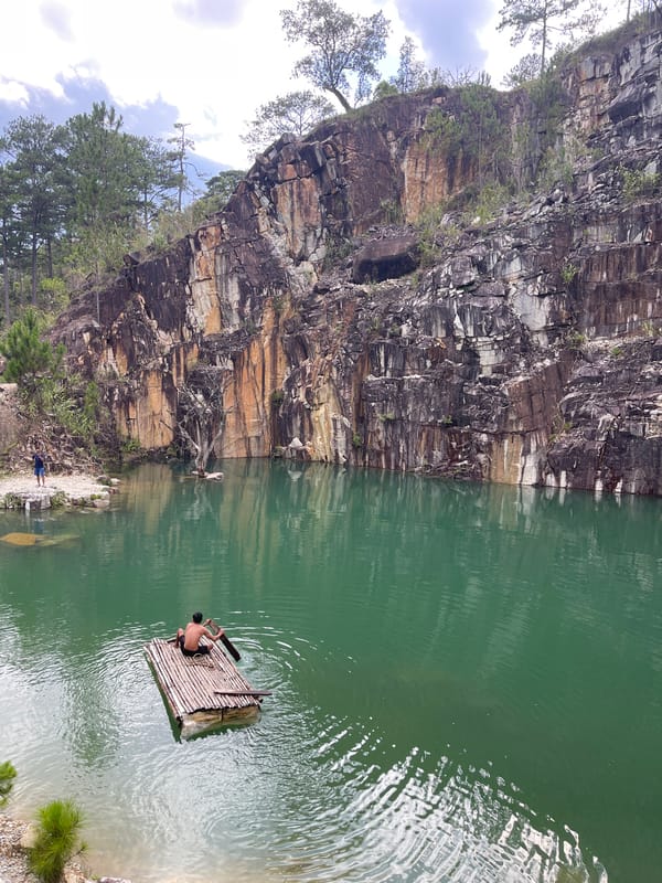Man paddles bamboo raft in Vietnam quarry waters