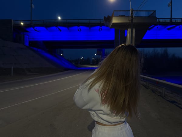 Person observes blue-illuminated bridge at night in April 2026