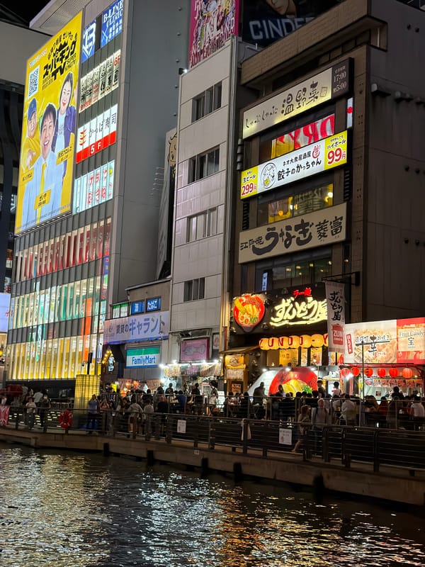 Neon-lit Osaka canal district bustling with nighttime activity