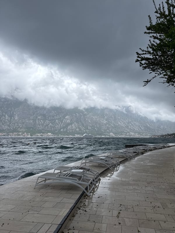 Couple walks pier in stormy Prčanj, Montenegro waterfront