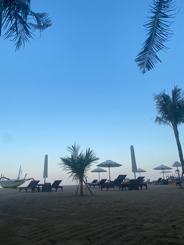 Quiet morning at a Denpasar beach — chairs, bikes, and shade