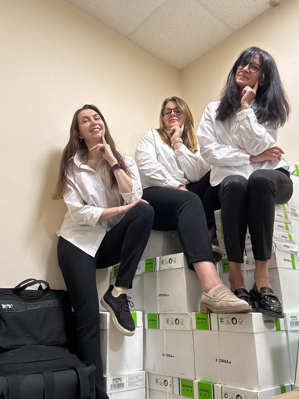 Three women rest on stacked boxes in storage space