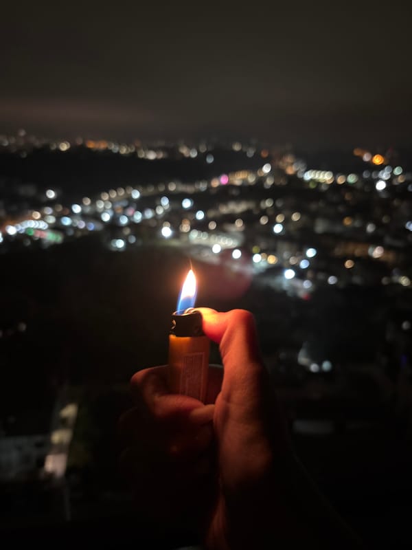 Person holds lit lighter against city lights in Sochi