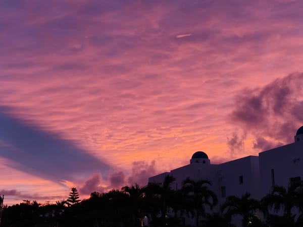 Miyakojima sunset behind palm trees and blue-domed building