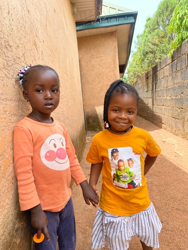 Two girls share fruit during morning play in Kuru, Nigeria