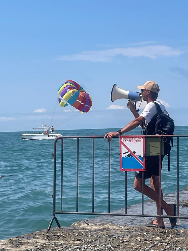 Crowded Sochi beach scene with megaphone address from pier