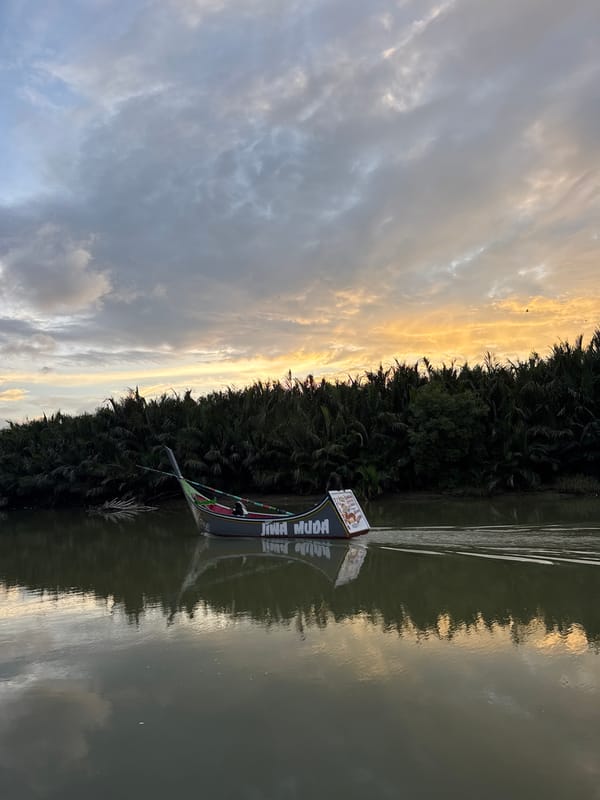 Boat 'JIWA MUDA' glides down a calm river at sunset
