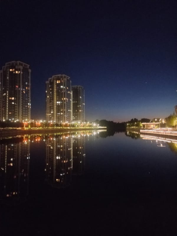 Illuminated buildings reflect in Kyiv waterway at night