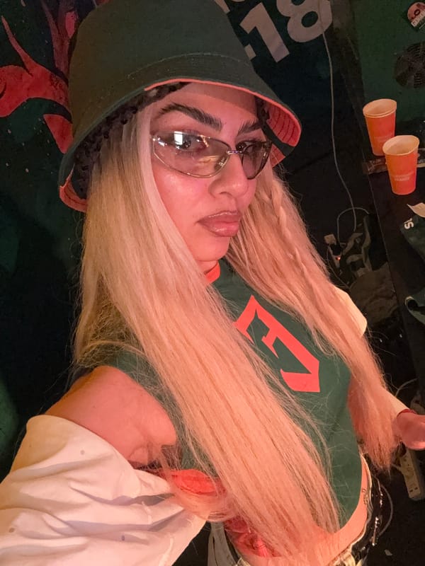 Green bucket hat and clear glasses in a dim indoor setting