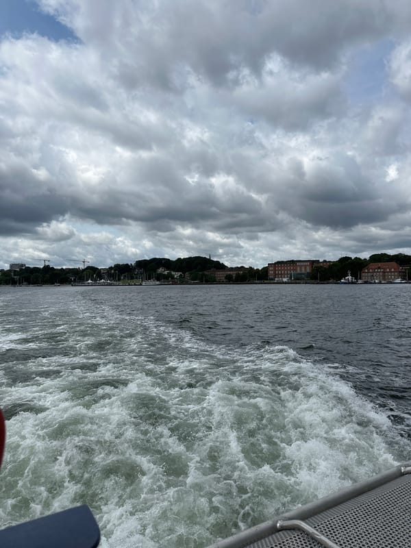 Out on Kiel Fjord, city skyline receding behind a moving boat