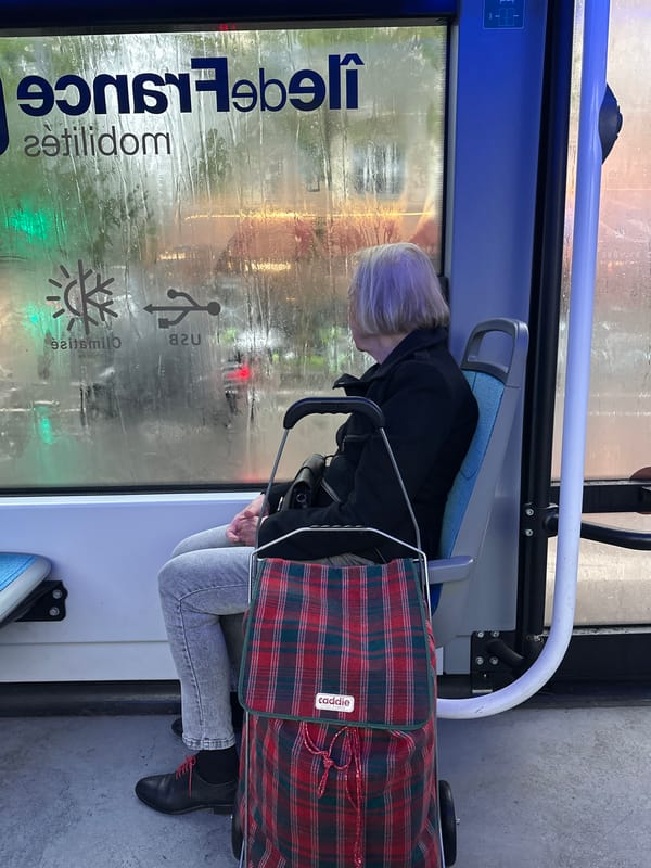 Elderly passenger rides Paris bus during rainy afternoon
