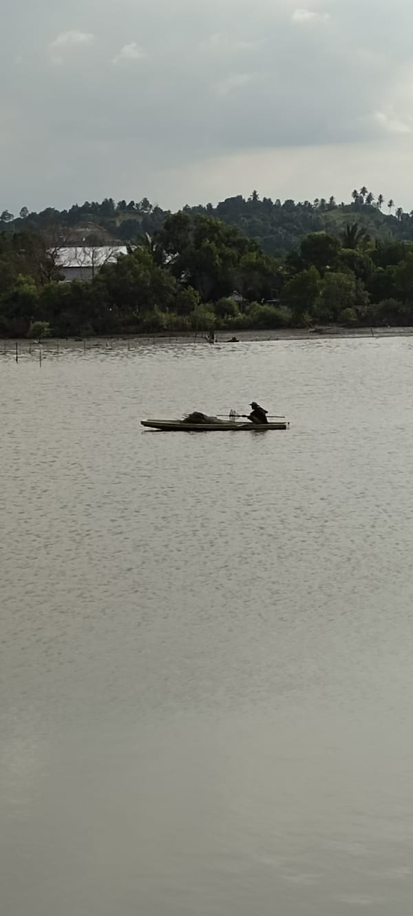 Lone paddler on glassy coastal waters off Lhokseumawe