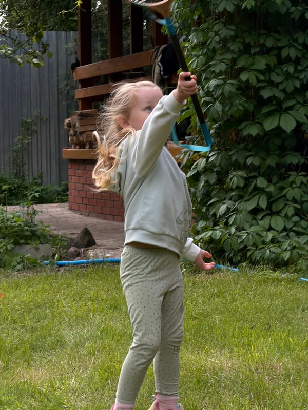 Child plays badminton in Russian village yard, fire burns nearby