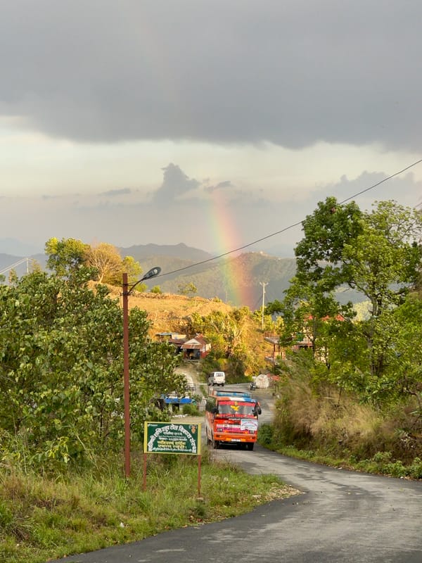 Rainbow arcs over Pokhara mountains amid cloudy Nepal skies