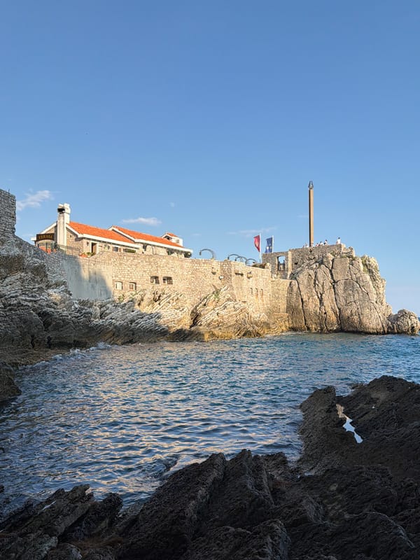 Petrovac's beach, harbor, and fortress on a busy summer afternoon