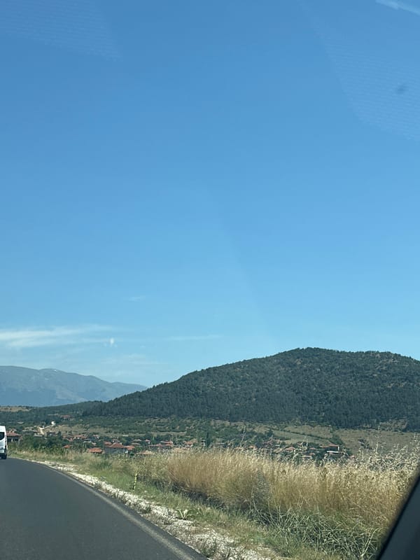 Quiet rural road curves through dry summer landscape in Bulgaria