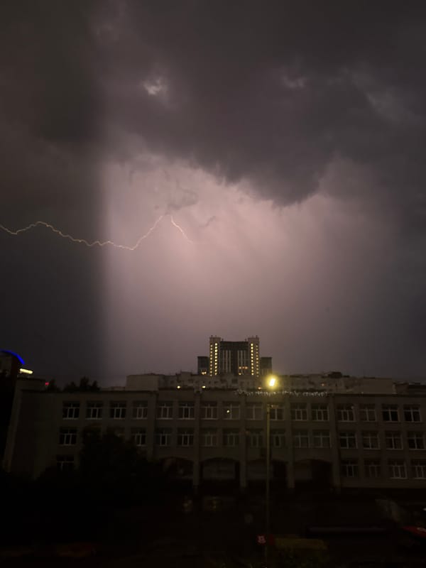 Thunderstorm with lightning strikes over city buildings