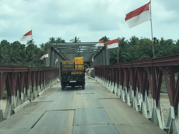 Black pickup with yellow cargo crosses bridge in Indonesia