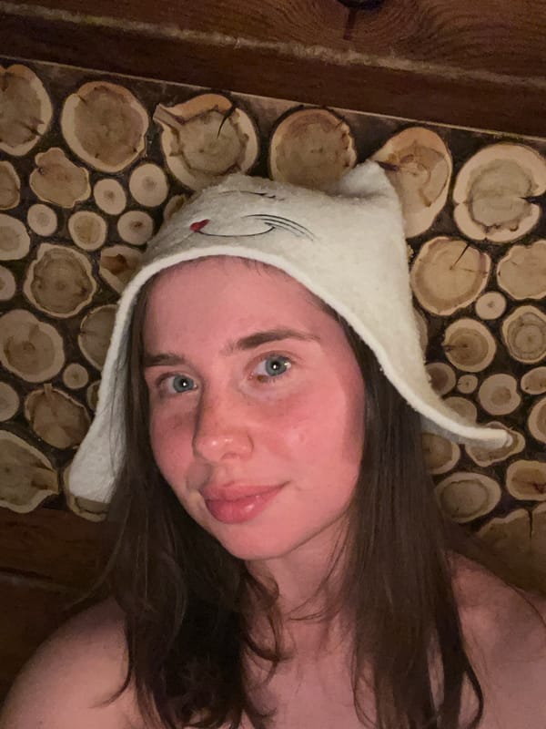 Woman documents sauna session wearing cat hat in Chaikovsky