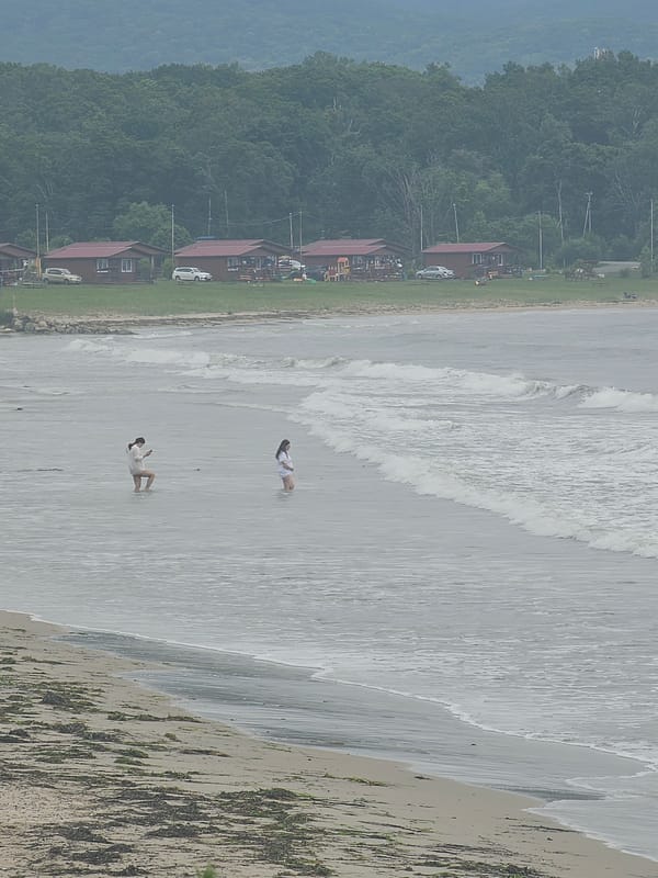 Wading in calm grey water on a cloudy Fokino beach