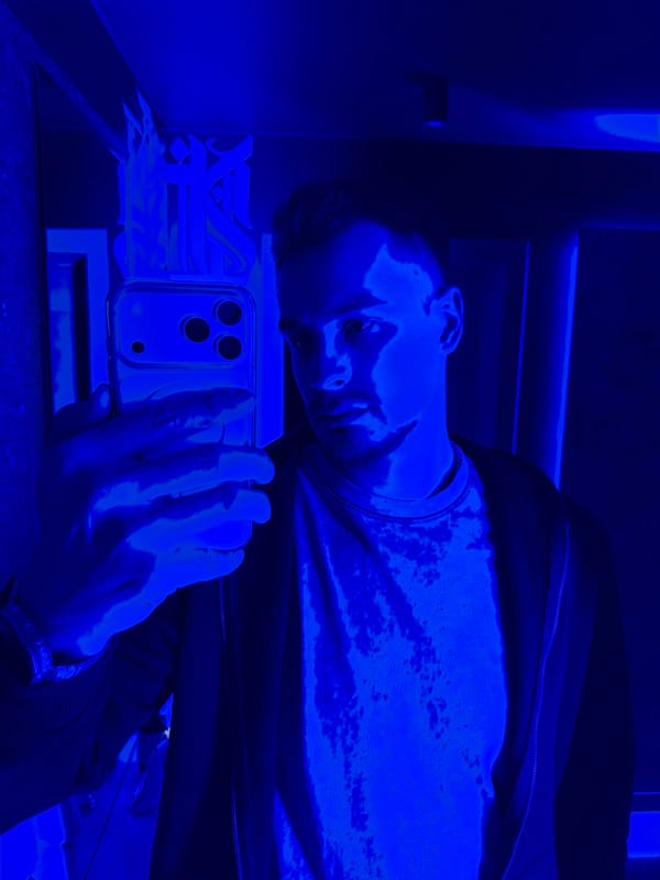 Man photographs with smartphone in dimly lit indoor setting