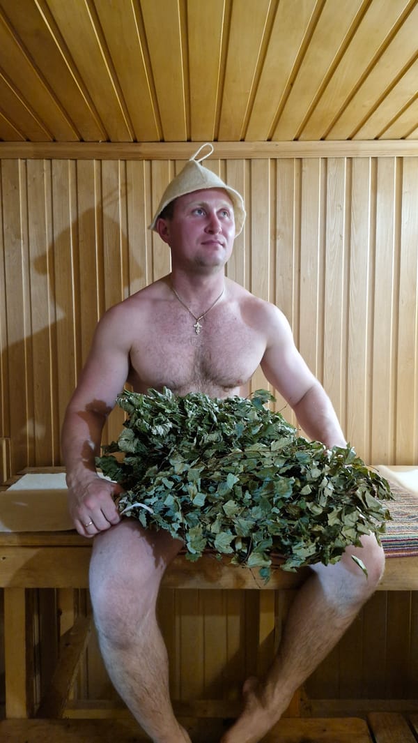 Man with leafy branches observed in traditional sauna setting