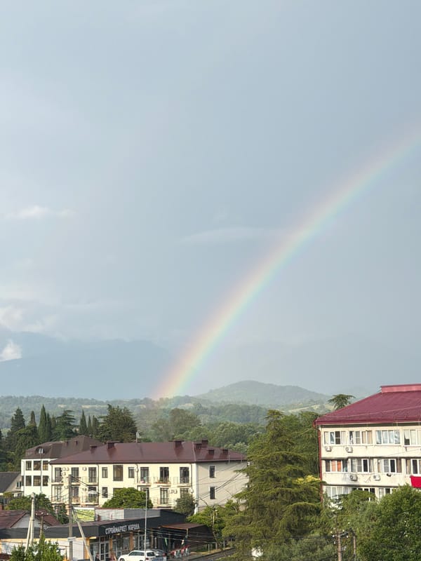 Rainbow over Sochi skyline with mountain backdrop