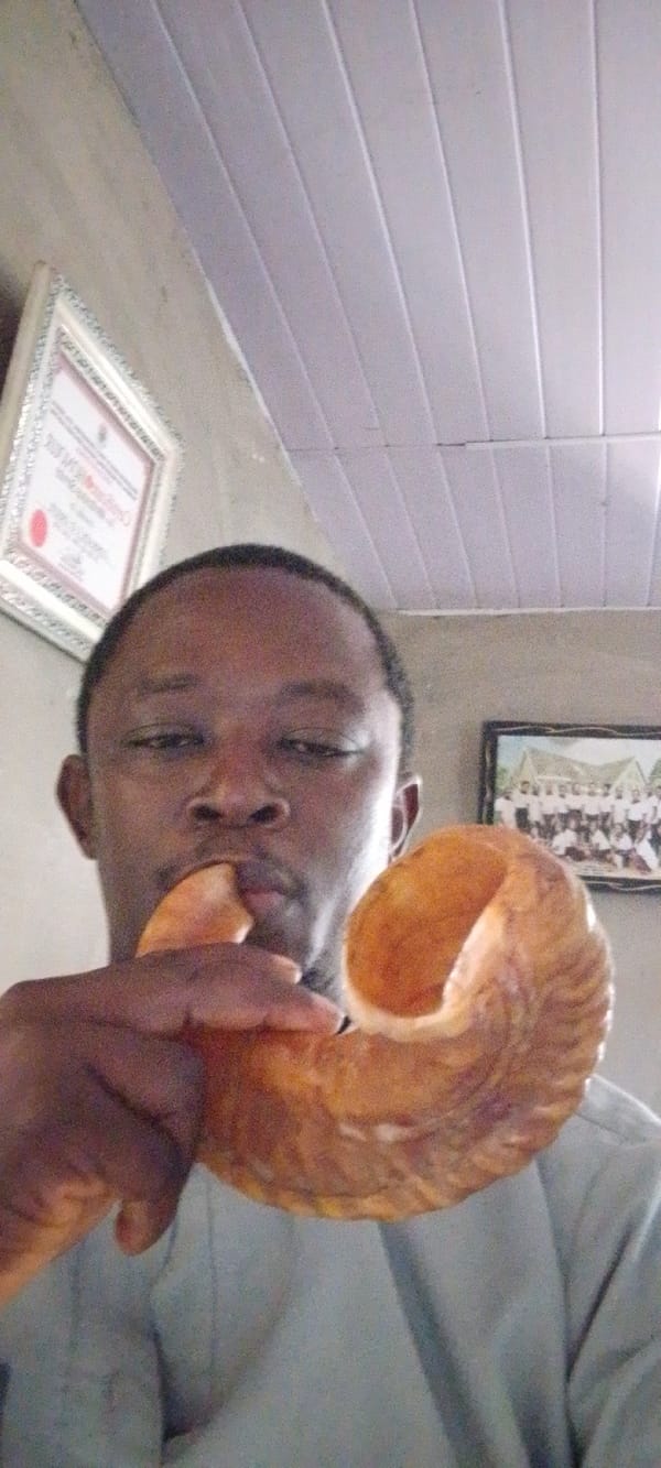 Man blows shofar indoors in ceremonial observance