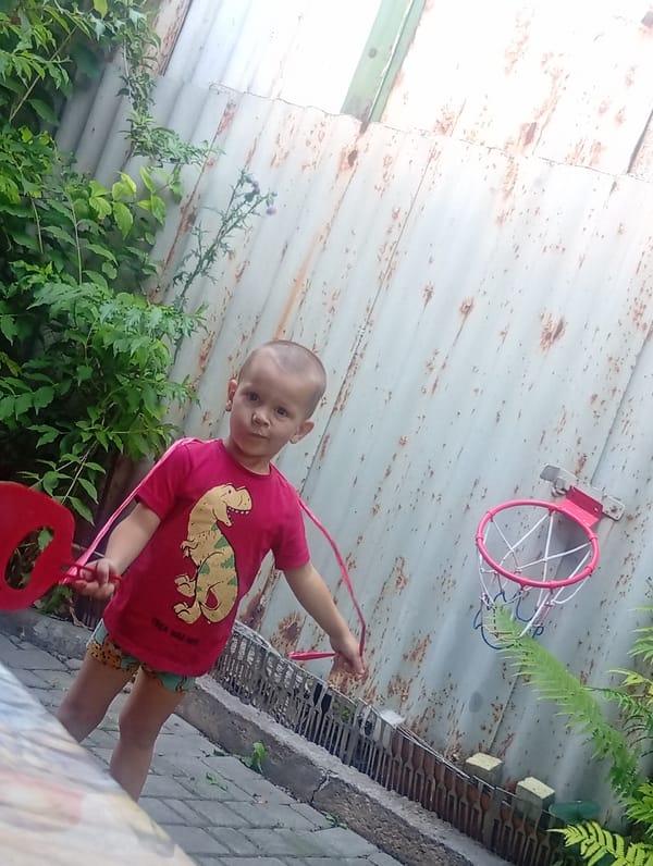 Backyard play with a broom and dinosaur tee