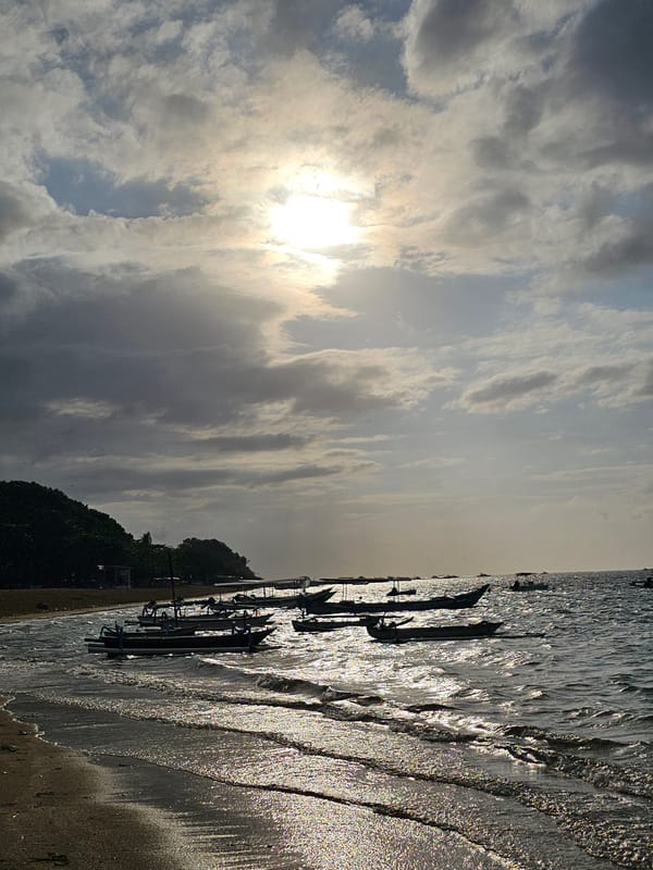 Kitesurfing and fishing boats off a Bali beach