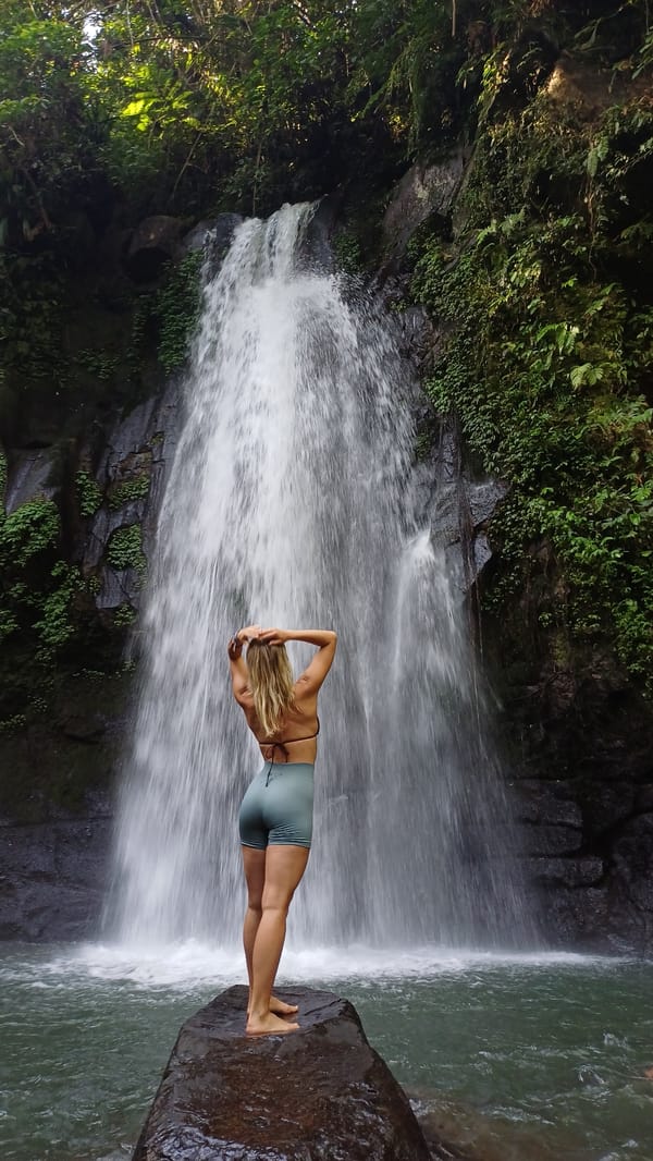 Woman poses at Tegallalang waterfall amid lush Bali scenery