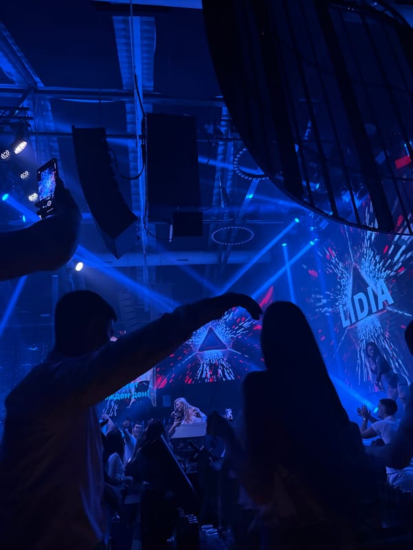 Nightclub scene with vibrant lighting and phone-wielding crowd